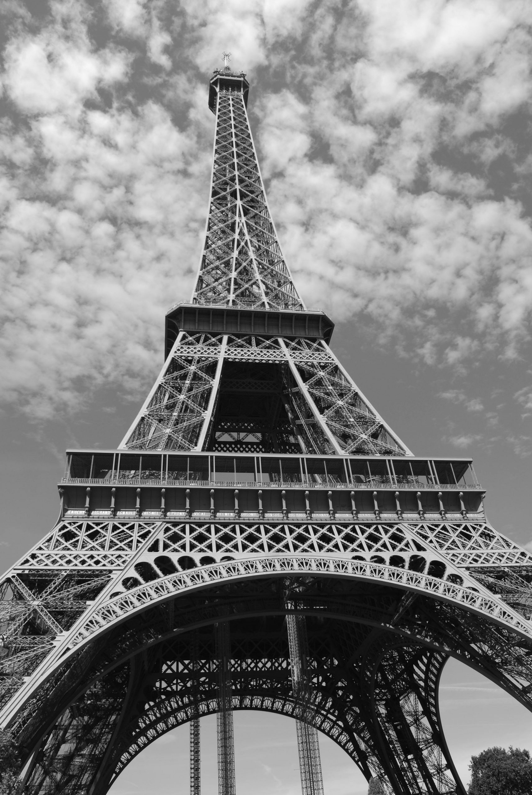Monochrome photograph of the Eiffel Tower viewed from below on a cloudy day.