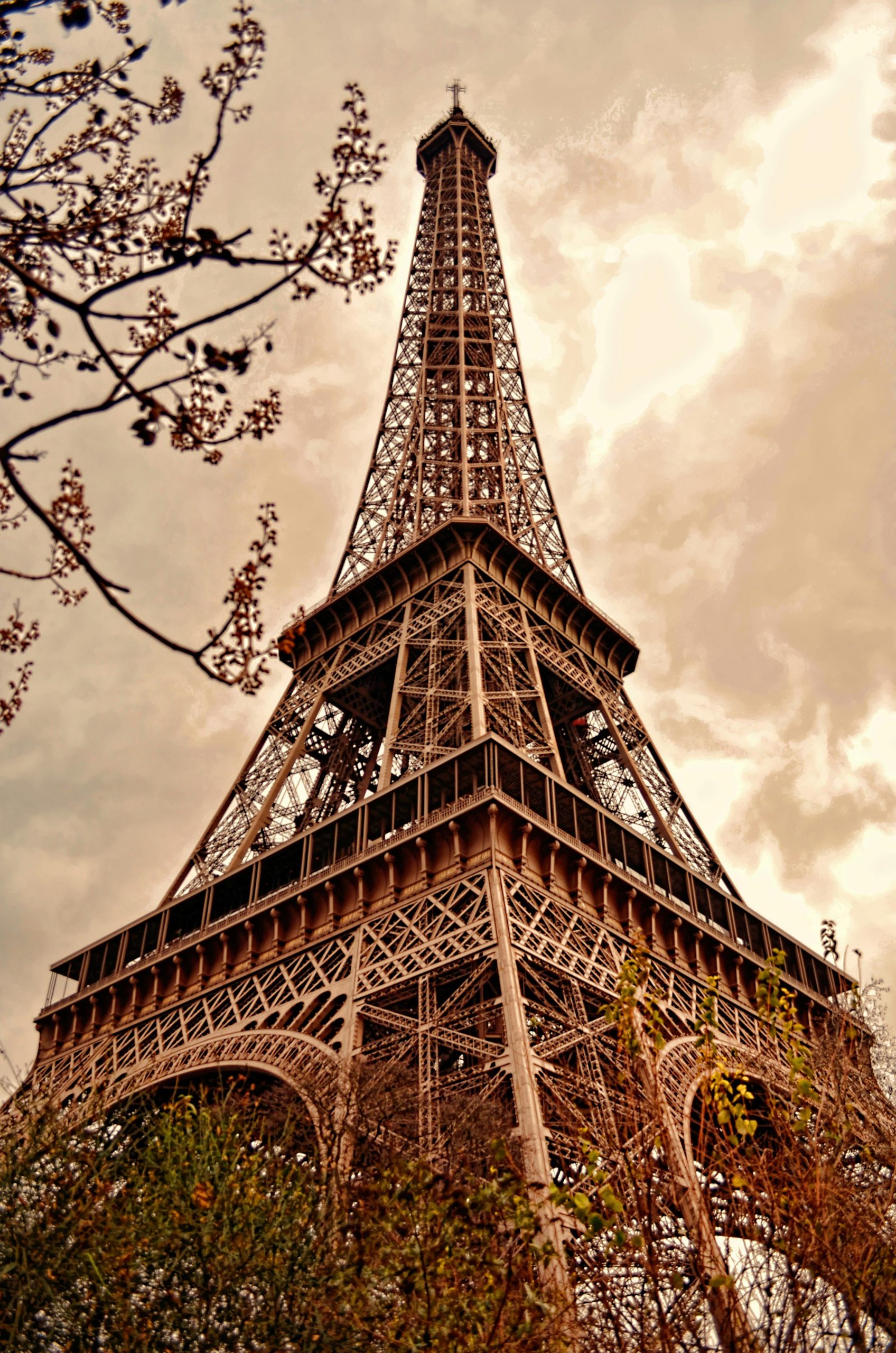 Low angle view of the Eiffel Tower against a dramatic sepia-toned sky in Paris.